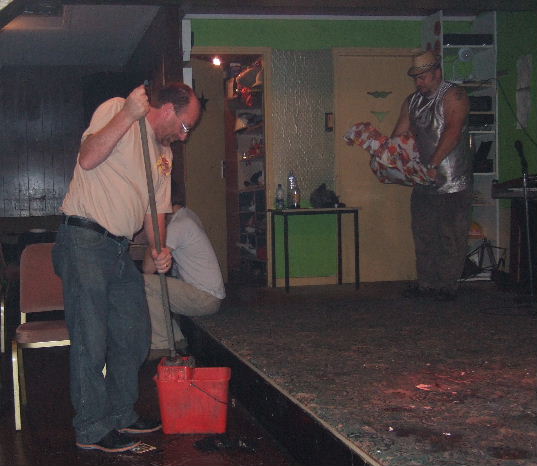 A man mops the floor in front of a low stage.